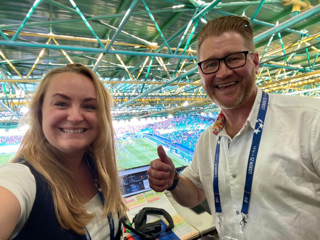 Katie, a photo of the first ever woman to Audio Describe a Women’s UEFA soccer club final match.
