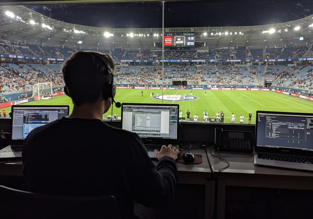 Man broadcasting live ADC commentary at a soccer game in a stadium